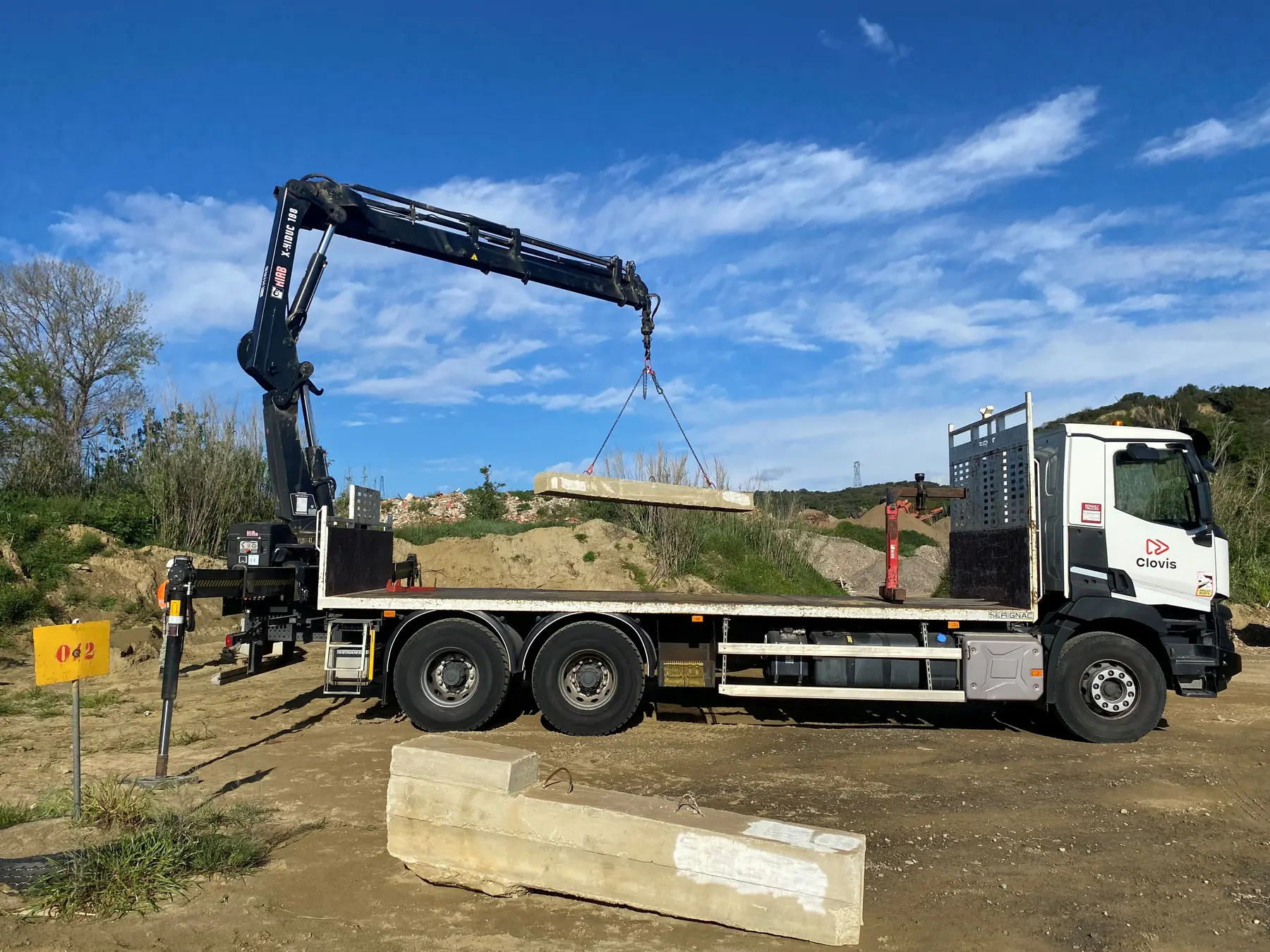 Camion-grue déposant un élément béton sur le chantier école