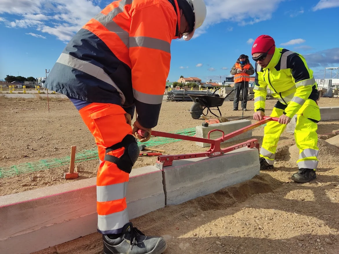 Deux apprentis posent une bordure sur le chantier école